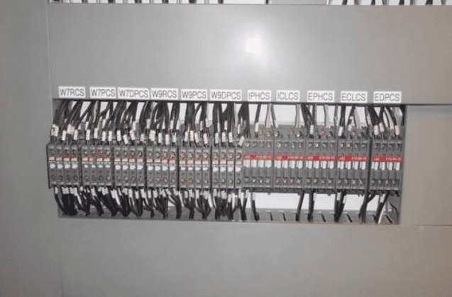 A neatly organized panel of electrical controls, labeled wires, and cables.