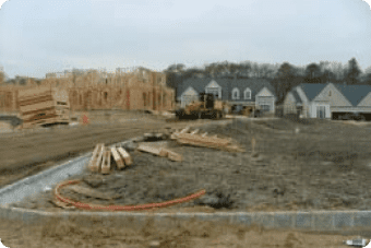 Residential construction site with partially built wooden structures and building materials in the foreground, undergoing groundwater remediation.