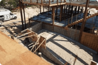 Construction site with unfinished concrete foundations, wooden formwork, and groundwater remediation.