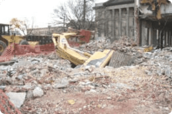 Demolition site with rubble, heavy machinery, and groundwater remediation equipment.