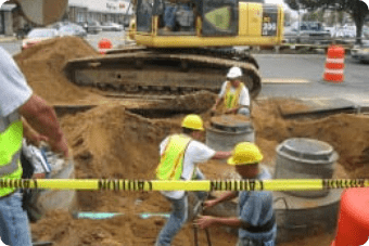 Construction workers in hard hats engaging in environmental cleanup at a road construction site.