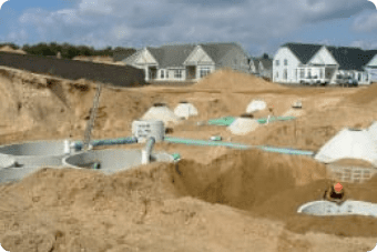 Residential construction site with incomplete in-ground pools and houses in the background, undergoing groundwater remediation.