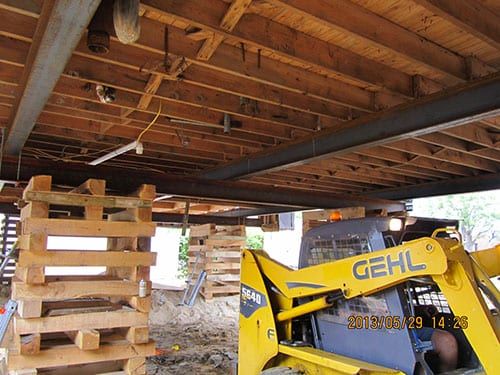 Construction equipment supporting a wooden structure during repair work with holzmacher engineering services.